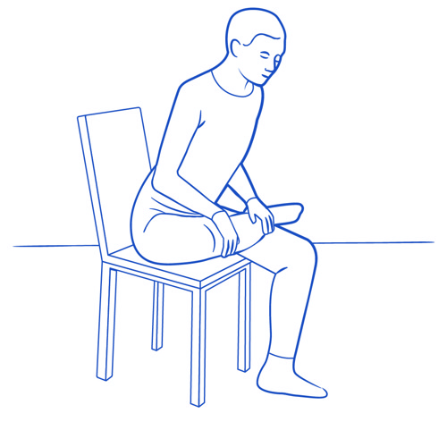En person sitter på en stol och lägger upp ena foten på motsatt knä för att stretcha stjärtmuskeln.