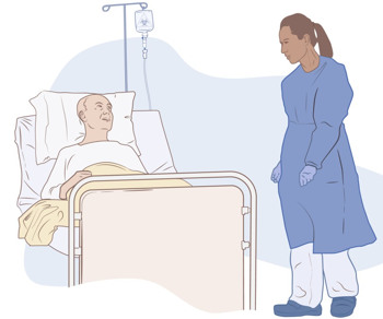 En patient som ligger i sjukhussäng med dropp och en vårdpersonal i skyddskläder som står bredvid. 